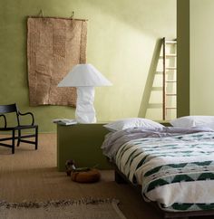 a room with a bed, chair and ladder in the corner on the wall next to it