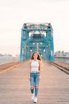 a woman standing on a bridge with her hair blowing in the wind and looking at the camera