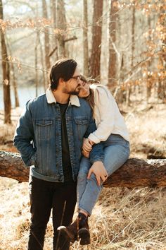 a man and woman sitting on a log in the woods