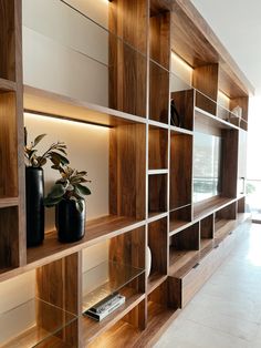 a wooden shelf with two vases on it and some bookshelves in the background