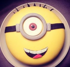 a yellow and black cake with an evil eye on it's face in the shape of a minion