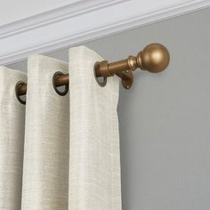 the curtain rod is attached to the side of the window with two brass knobs