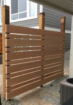 a wooden slatted fence in front of a house with an air conditioner