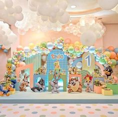 an elaborate birthday party with balloons and animals on the stage for children's first birthday