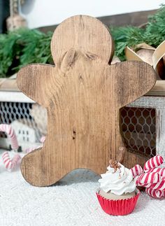 a wooden gingerbread man standing next to cupcakes and candy canes on a table