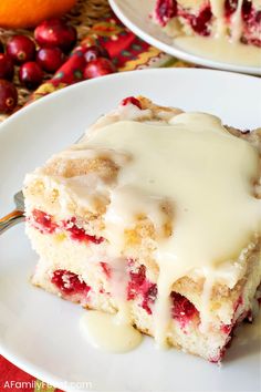 a piece of cake on a white plate with icing and cranberry sauce