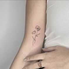 a woman's left arm with a single flower tattoo on the right side of her arm