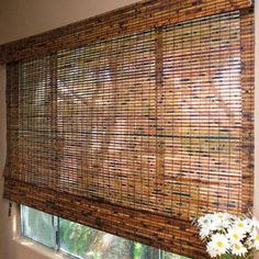 a window with bamboo blinds on it and flowers in front of the windowsills