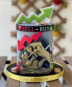 a cake in the shape of a can with an elephant on it and some gold coins