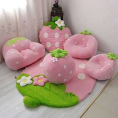 pink and green strawberry shaped pillows sitting on top of a white floor next to a window