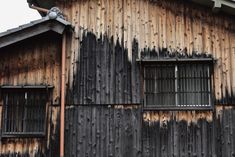 an old wooden building with windows and bars on the side