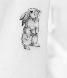 a black and white photo of a rabbit tattoo on the right inner arm, with an outline of a bunny in the middle