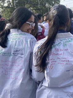 two women in white jackets with writing on their backs, and one woman wearing sunglasses