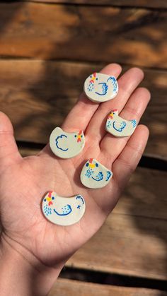 a person's hand holding five small white buttons with blue and yellow designs on them