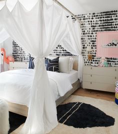 a white canopy bed in a bedroom with black and white wallpaper