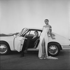 a man and woman standing next to a car