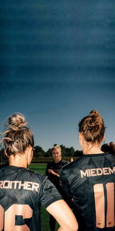 two women in black jerseys standing on a field