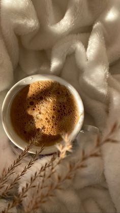 a cup of coffee sitting on top of a white blanket