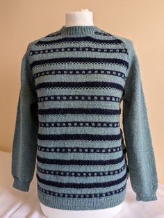 a blue and black sweater sitting on top of a white mannequin