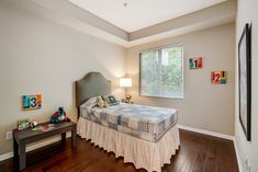 a bed room with a neatly made bed and wooden floors