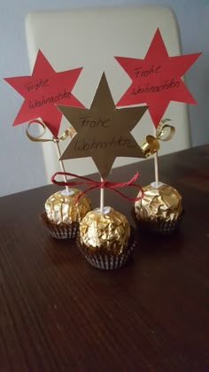 three chocolates wrapped in gold foil with red stars on top and one has a sign that says, thank you