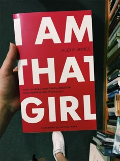 the book i am that girl is being held up in front of a bookshelf