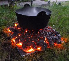 a large pot sitting on top of a fire pit in the middle of a field