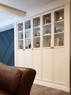 a brown leather chair sitting in front of a white bookcase with glass doors on it