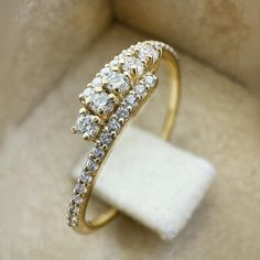 a diamond ring sitting on top of a white cloth in a box with its lid open