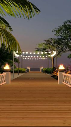 a wooden walkway with lights and palm trees