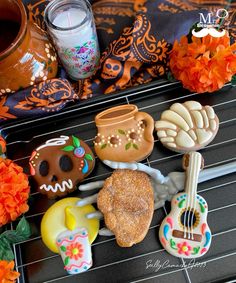 decorated cookies are sitting on a rack next to candles and vases with orange flowers