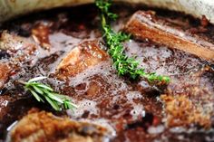 a pot filled with meat and vegetables covered in gravy, garnished with parsley