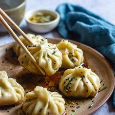 some dumplings are on a plate with chopsticks