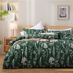 a bed with green and white comforter in a bedroom next to a plant on the wall