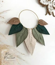 a green and beige necklace with leaves hanging from it