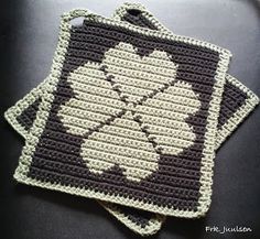 two crocheted coasters sitting on top of a black table next to each other