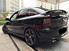 a black car parked in front of a building with its trunk open and the hood up