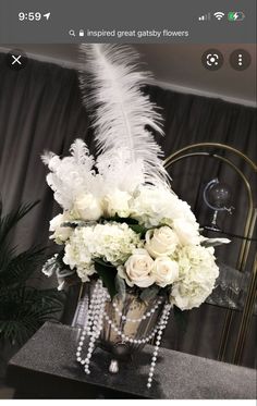 a vase filled with white flowers on top of a table next to a tall plant