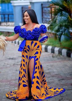 a woman in an orange and blue dress is holding a small dog's tail