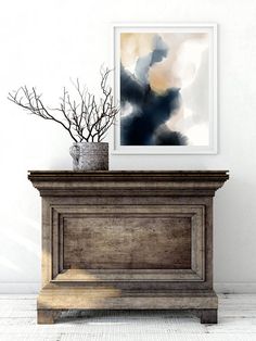 a painting is hanging on the wall next to a wooden chest with branches in it