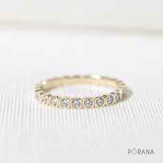 a yellow gold wedding band with five round diamonds on the inside and outside, sitting on a white surface