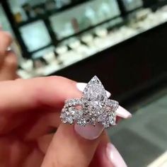 a woman's hand holding a diamond ring in front of a jewelry store display