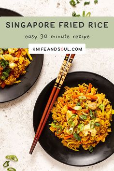 two black plates topped with rice and vegetables next to chopsticks on a white table