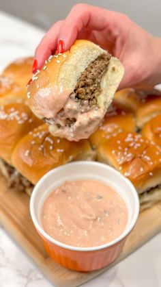 a person is dipping some kind of meatball into a bun on a cutting board