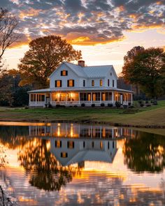 a large white house sitting on top of a lush green field next to a lake