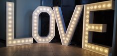 lighted letters spelling love on the floor in front of a wall with light up letters