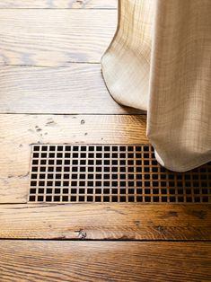 a wooden floor with a grate in the middle and a curtain hanging off it's side