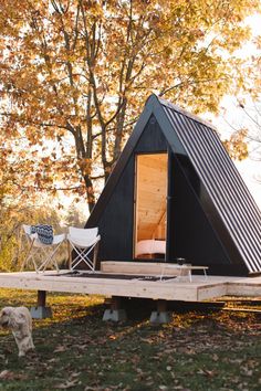 a small black cabin sitting on top of a lush green field