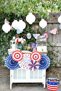 a table with red, white and blue decorations on top of it in front of a fence