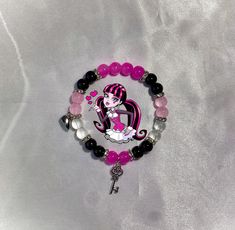 a bracelet with pink and black beads on it, featuring a cartoon character holding a key